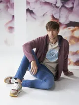 Buzo tipo hoodie con cierre frontal completo, capucha con cordones ajustables y bolsillos laterales. Confeccionado en tejido de algodón con textura jaspeada.