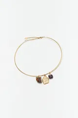 Collar rígido dorado con tres dijes colgantes de piedra natural: uno de ojo de tigre, uno dorado con textura irregular y uno de ónix.
