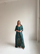 Vestido largo verde petróleo con estampado floral grande en tonos marrones y ocres, de corte amplio, mangas tres cuartos y escote en V.
