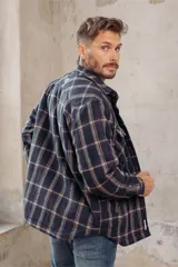 Sobrecamisa de corte holgado con diseño a cuadros en tonos azul marino y marrón, confeccionada con forro interior de corderito sintético, cuello clásico, cierre frontal de botones y bolsillos en el pecho.