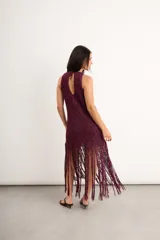 Vestido midi de crochet bordó con destellos de lurex, de cuello redondo y sin mangas, con falda terminada en largos flecos trenzados a mano.
