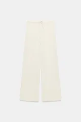 Pantalón palazzo de tiro medio, color crudo, con textura y cintura elástica ajustable con cordón. Pierna ancha y fluida.