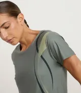 Remera deportiva de microfibra en color verde grisáceo, con cuello redondo, mangas cortas y detalle de estampa lateral con ondas en tonos contrastantes.