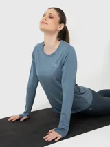 Polera deportiva de manga larga con cuello redondo, confeccionada en tejido técnico de efecto jaspeado. Presenta aberturas para los pulgares en los puños y un pequeño logo bordado en el pecho.