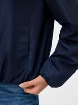 Campera bomber corta color azul marino, con cuello redondo, cierre frontal de cremallera y bolsillos delanteros. Confeccionada en tejido plano y completamente forrada.