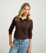 Blusa polo de manga larga color marrón, confeccionada en tejido interlock, con cuello tortuga y cierre frontal parcial con botones.