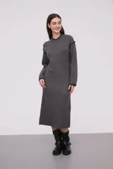 Vestido midi gris de tejido de punto, con cuello redondo y mangas largas. Presenta ribete negro en cuello, puños y hombros.