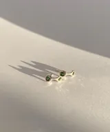 Aritos plateados con tres piedras verdes.