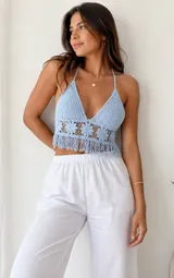 Top halter de crochet en color celeste, con escote en V pronunciado, diseño tejido con detalles de flores en la parte inferior y terminación con flecos.