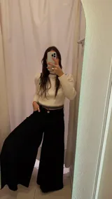 Pantalón palazzo negro de tiro alto con pinzas delanteras y bolsillos laterales.