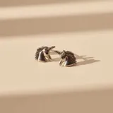 Aros tipo caravana con diseño de unicornio, fabricados en plata 925 con detalle de circonia negra en el ojo.