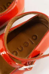 Chatas rojas de cuero charol, con pulsera al tobillo con hebilla y suela color caramelo.