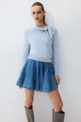 Buzo en punto fino de mezcla de viscosa color celeste, modelo entallado con cuello pañuelo integrado y remate acanalado en puños y bajo.