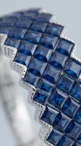 Anillo de plata 925 con diseño de banda ancha, engastado con múltiples circonias azules en un patrón geométrico entrelazado.