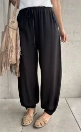 Pantalón negro tipo babucha con cintura elástica fruncida y cordón ajustable, corte holgado y puños elásticos en los tobillos.