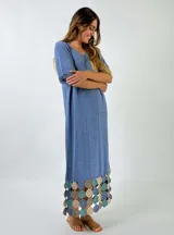 Vestido midi de tejido ligero color beige, con cuello en V, mangas cortas y ruedo decorado con aplicaciones de crochet en tonos tierra y rosado.