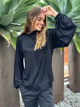 Blusa de manga larga color azul oscuro, con cuello alto y textura arrugada o plisada. El calce es holgado y las mangas terminan con elástico en la muñeca.