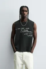 Camiseta sin mangas (tank top) negra, corte boxy fit, con cuello redondo y sisa con acabado irregular. Presenta un estampado frontal con texto manuscrito en verde y blanco que dice: "I look cool online, but offline I'm even better... Chase real likes!".