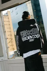 Hoodie negro con cierre, corte regular y lavado gastado. Estampado con logo en el pecho y diseños en las mangas.