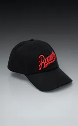 Gorra de gabardina negra con visera curva y bordado frontal en hilo rojo con la palabra "Ravers" en tipografía cursiva. Posee ajuste trasero de velcro.