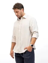 Camisa de manga larga confeccionada en 100% lino natural, con cuello clásico y cierre frontal de botones. Presenta un calce relajado y una textura ligera, ideal para climas cálidos.