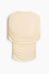 Top entallado de punto suave en color beige, con cuello tortuga, capa decorativa superpuesta y frunces laterales que generan un efecto drapeado.