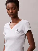 Remera de corte slim confeccionada en punto de algodón elástico con textura de canalé fino. Presenta cuello en V, manga corta y una insignia con el logo de Calvin Klein en el pecho.