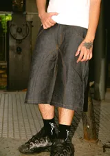 Bermuda de jean rígido color azul oscuro, corte baggy, con costuras contrastantes en color camel. Presenta un bordado estilizado en hilo blanco en el bolsillo trasero derecho.