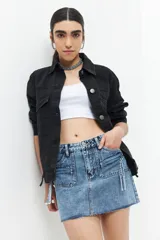 Minifalda de jean celeste con lavado ácido, cuatro bolsillos delanteros (dos con cierre) y ruedo desflecado.