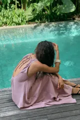 Vestido midi de corte fluido, cuello redondo y diseño sin mangas. Presenta una abertura en la espalda con cierre de lazada ajustable.