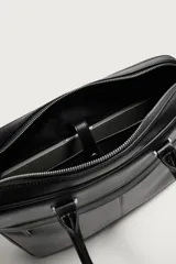 Maletín slim de color negro con acabado grabado, compartimento principal con cierre de cremallera, bolsillo interior para portátiles de hasta 13 pulgadas, bolsillo frontal con cierre, dos asas de mano y asa de hombro ajustable y extraíble.