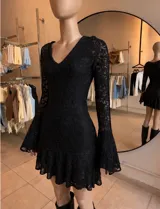 Vestido corto negro de encaje con escote en V, mangas largas acampanadas y falda con volado en el ruedo.