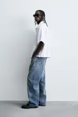 Camisa de manga corta confeccionada en tejido de cáñamo, con calce relajado. Presenta cuello solapa, cierre frontal con botones y dos bolsillos de plastrón en la parte inferior delantera.