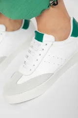 Zapatillas acordonadas de cuero color blanco con puntera de gamuza gris y detalles en verde.