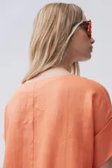 Vestido midi azul de lino, corte recto, escote en V, mangas cortas, bolsillos laterales y tajos laterales. Incluye un pañuelo estampado atado a la cintura.