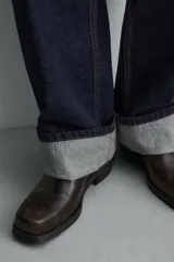 Bota estilo cowboy con acabado desgastado, tiradores laterales y horma cuadrada con tacón.