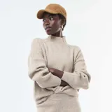 Sweater de punto canalé en color beige, con cuello alto y mangas largas con puños ajustados.