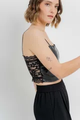 Top crop negro de cuero ecológico con espalda de encaje floral nude, tirantes finos y corte entallado.