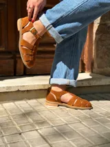Sandalias cangrejeras de gamuza color marrón, con diseño cerrado de tiras entrelazadas, talón cerrado y hebilla metálica ajustable en el tobillo.