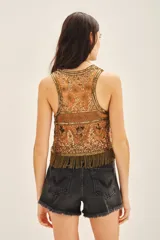 Top corto sin mangas con escote redondo, confeccionado en tul bordado con lentejuelas, piedras y canutillos. Presenta un diseño con flecos de mostacillas en el ruedo y una tira larga decorativa al cuello.