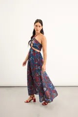 Vestido largo de gasa con estampado floral acuarelado en tonos azules y rojos, con escote halter, tiras regulables y detalles cut out en la cintura y el escote con apliques de cuentas.