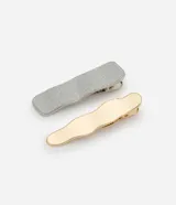 Set de dos pinzas para el pelo, una plateada con textura brillante y otra dorada con textura ondulada.