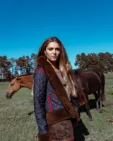 Campera acolchada de diseño artesanal, con detalles de piel sintética en cuello, puños y ruedo. Presenta costuras decorativas en crochet color rojo en los bolsillos y hombros, con cierre frontal.