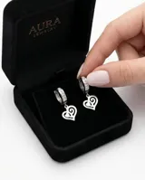 Caravanas tipo argolla de acero con incrustaciones de piedras brillantes y dije colgante en forma de corazón con diseño calado.