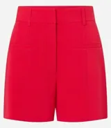 Bermuda femenina de sastrería color rojo, confeccionada en tejido de crepé. Presenta trabillas en la cintura, cierre delantero y bolsillos falsos.