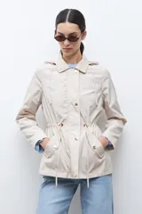 Campera impermeable color negro con capucha desmontable, cuello alto, cierre frontal con botones a presión y cordón ajustable en la cintura.