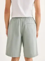 Bermuda de corte recto en color negro, confeccionada en tejido de algodón, con cierre frontal y bolsillos laterales.