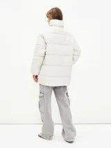Campera puffer color blanco hueso, con cuello alto, cierre frontal con cremallera y bolsillos laterales con cierre.