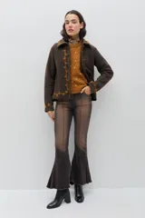 Chaqueta de lana merino hervida en color marrón, con diseño estructurado y cuello amplio. Presenta detalles de bordado artesanal en contraste color mostaza a lo largo del frente, cuello y puños, junto con botones forrados en la misma tela.