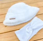 Set de gorro tipo bucket y vincha, ambos de color blanco. El gorro es de tela peluche y la vincha es de tela tejida con nudo frontal.